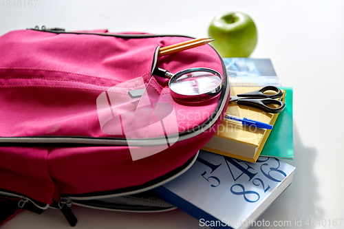 Image of backpack with books, school supplies and apple