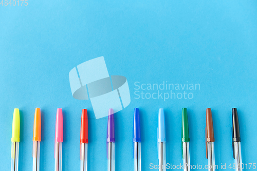 Image of row of multicolored pens on blue background