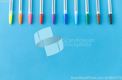 Image of row of multicolored pens on blue background