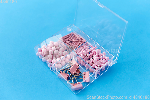 Image of pins and clips in plastic pox on blue background