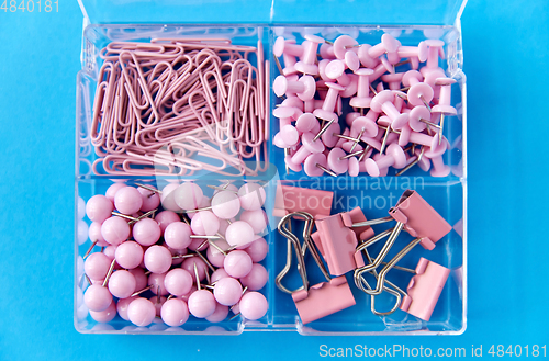 Image of pins and clips in plastic pox on blue background