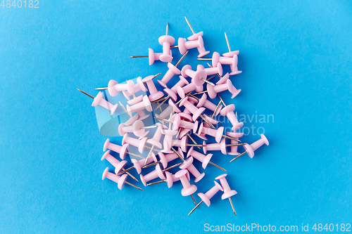 Image of heap of pink office pins on blue background