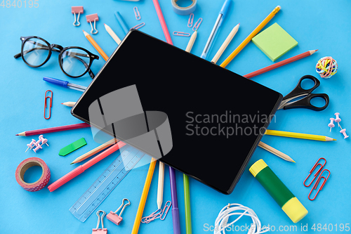 Image of tablet pc and school supplies on blue background