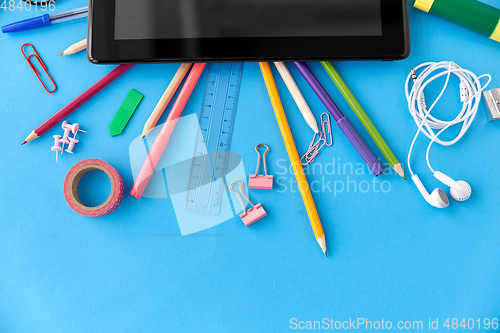 Image of tablet pc and school supplies on blue background