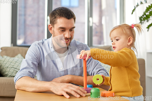 Image of father playing with little baby daughter at home