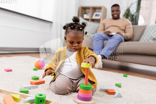 Image of african baby girl playing with toy blocks at home