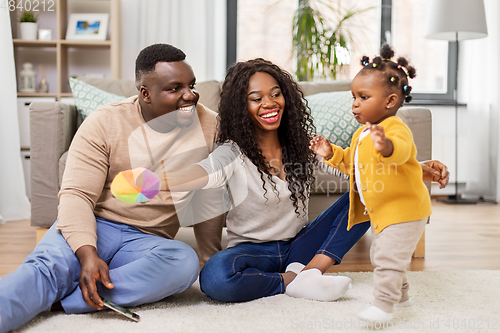 Image of african family playing with baby daughter at home