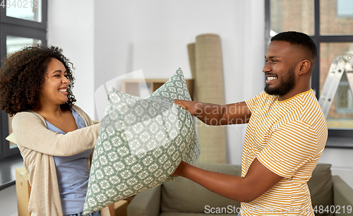 Image of happy couple having pillow fight at new home
