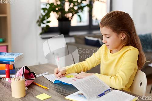 Image of student girl with book writing to notebook at home