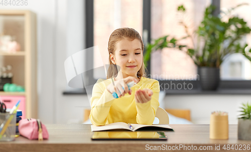 Image of little student girl with hand sanitizer at home
