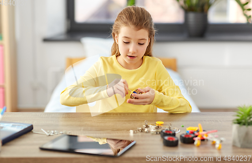 Image of happy girl playing with robotics kit at home