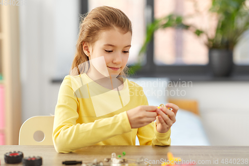 Image of happy girl playing with robotics kit at home