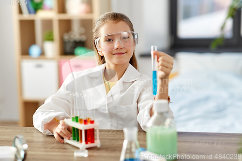 Image of girl with test tube studying chemistry at home