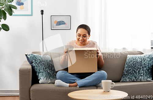 Image of african american woman opening parcel box at home