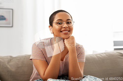 Image of african american woman in glasses sitting on sofa