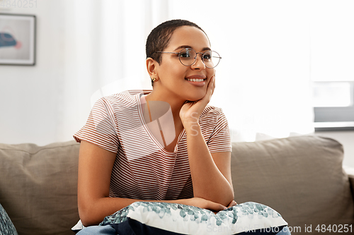 Image of african american woman in glasses sitting on sofa