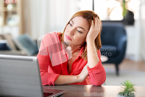 Image of bored woman with laptop working at home office