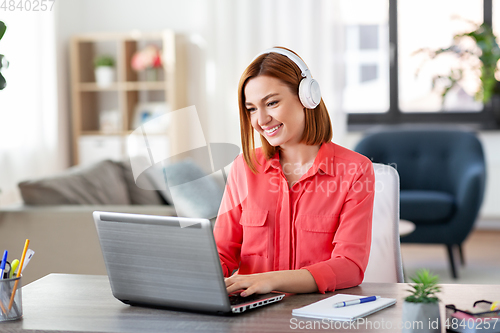 Image of woman in headphones with laptop working at home