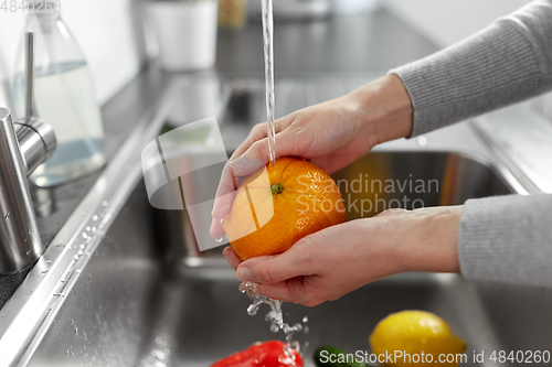 Image of woman washing fruits and vegetables in kitchen