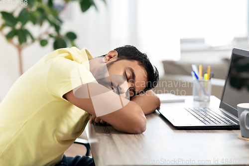 Image of indian man sleeping on table with laptop at home