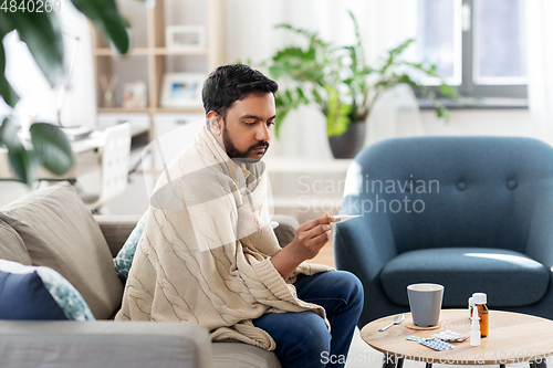 Image of sick man measuring temperature by thermometer