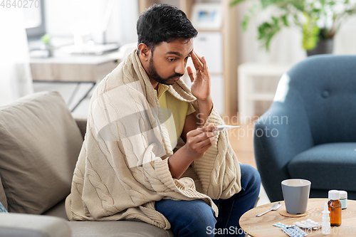 Image of sick man measuring temperature by thermometer