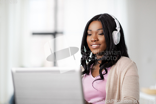 Image of woman in headphones with laptop working at home