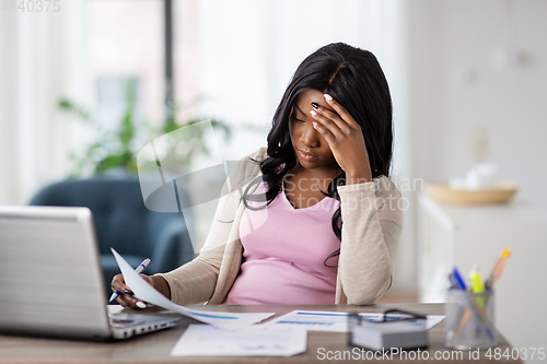 Image of stressed woman with papers working at home office