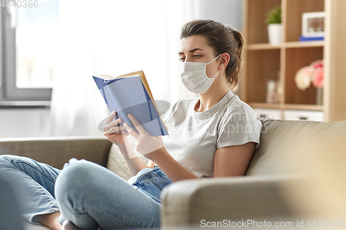 Image of sick woman in medical mask reading book at home