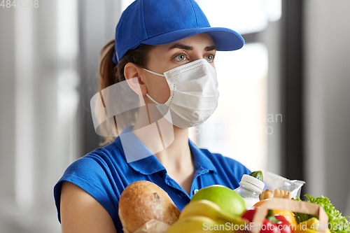 Image of delivery woman in face mask with food in paper bag