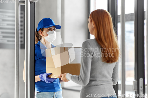 Image of delivery girl in face mask giving parcel to woman