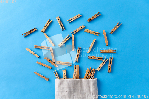 Image of wooden clothespins in bag on blue background