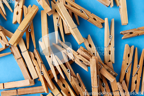 Image of close up of wooden clothespins on blue background