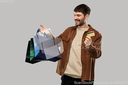 Image of happy young man with shopping bags and credit card
