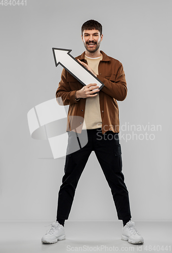 Image of smiling young man holding big white arrow