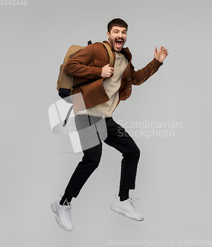 Image of smiling young man with backpack jumping in air