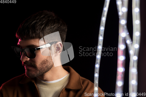 Image of man in sunglasses over neon lights at nightclub