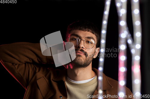 Image of man in glasses over neon lights at nightclub