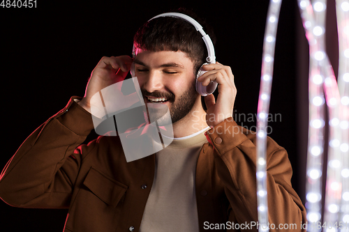 Image of man in headphones over neon lights of night club