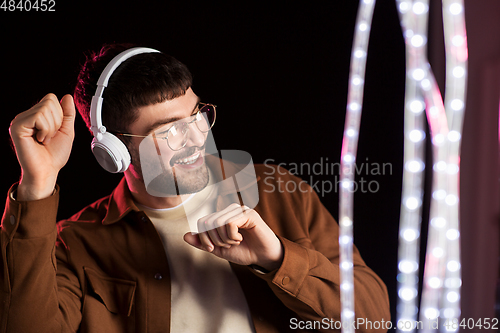 Image of man in headphones over neon lights of night club