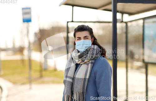 Image of young woman wearing medical mask at bus stop