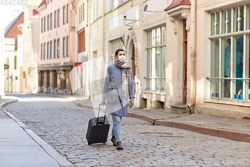 Image of woman in protective mask with travel bag in city