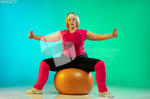 Image of Young caucasian plus size female model\'s training on gradient green background