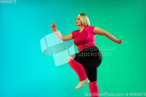 Image of Young caucasian plus size female model\'s training on gradient green background
