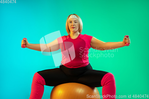 Image of Young caucasian plus size female model\'s training on gradient green background