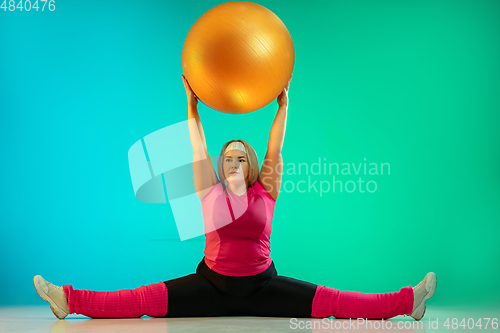 Image of Young caucasian plus size female model\'s training on gradient green background