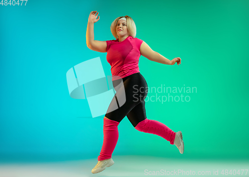 Image of Young caucasian plus size female model\'s training on gradient green background