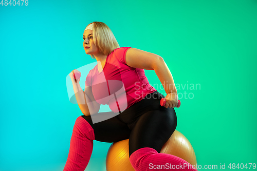 Image of Young caucasian plus size female model\'s training on gradient green background