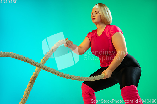 Image of Young caucasian plus size female model\'s training on gradient green background