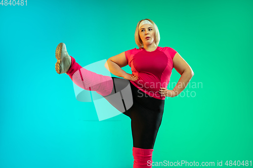 Image of Young caucasian plus size female model\'s training on gradient green background